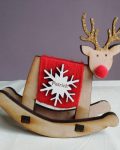 Rockin' Reindeer is a free-standing rocking brown wooden reindeer. Body wrapped in red wool, with a red pom pom nose and gold glittered antlers. It has a personalised white snowflake badge on its body with the name "Patrick" laser engraved in brown.